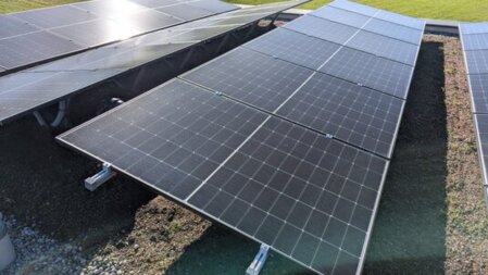 PV‑Anlage auf begrüntem Dach mit abgestimmtem Schichtaufbau und robusten Pflanzen zur Verbesserung von Kühlung, Leistung und Dachökologie.