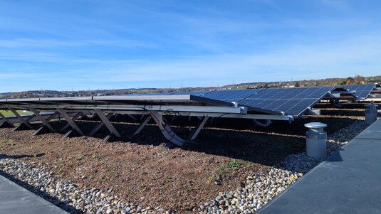 Gründach mit Sedum‑Bepflanzung und integrierter Photovoltaikanlage; ökologische Dachlösung mit verbessertem Solarertrag durch natürliche Kühlung.